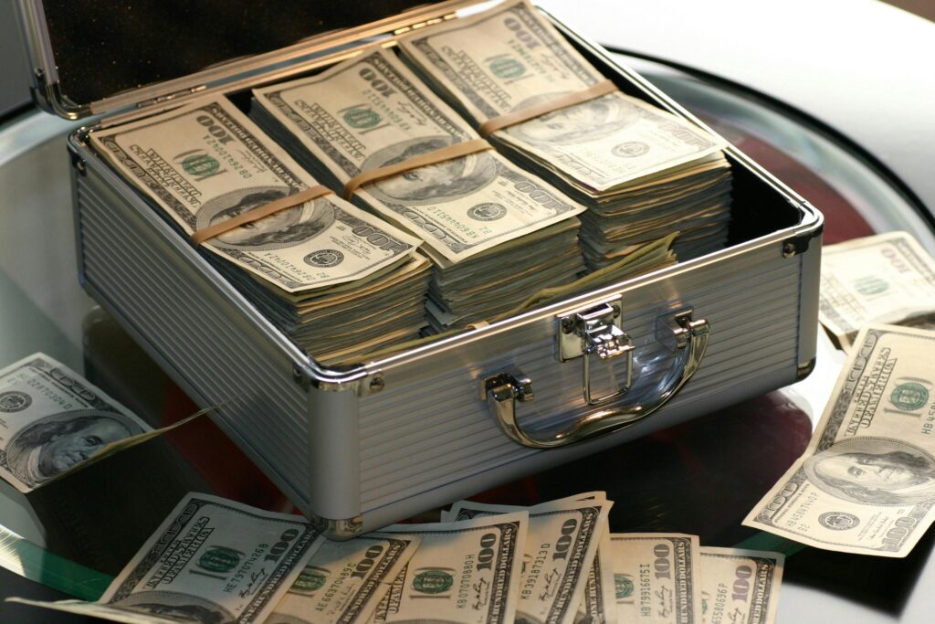 pexels-photo-259027-259027 Open briefcase filled with stacks of hundred dollar bills on a glass table, representing wealth.